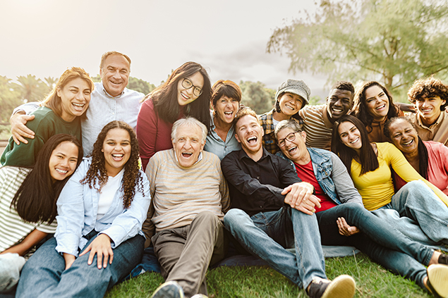 A multi-ethnic group of people sitting on the ground and smiling