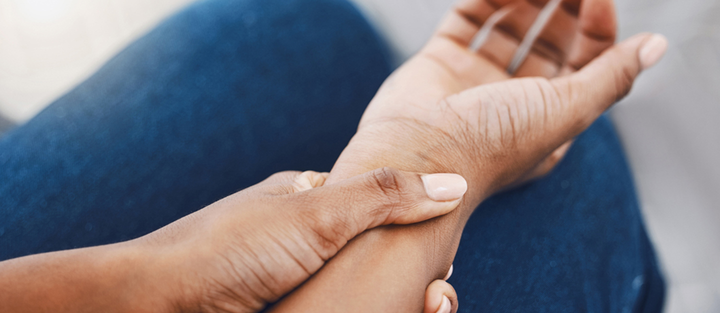 A person sitting down holding their wrist as if in pain